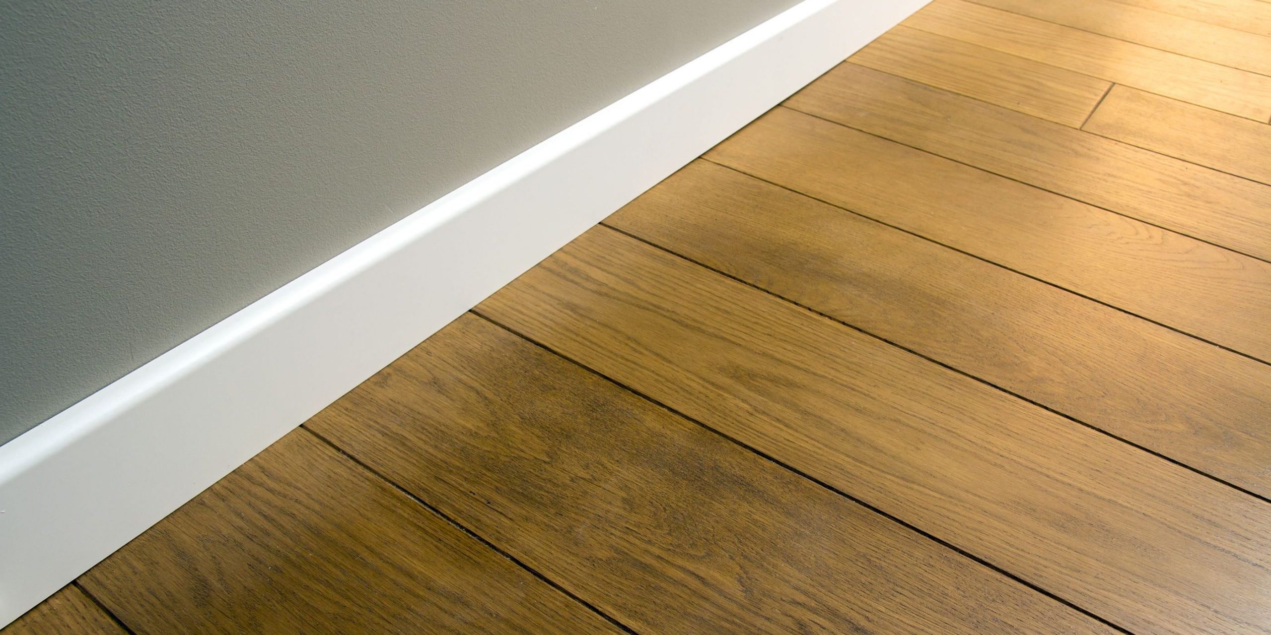 cerca-zocalos-plastico-blanco-sobre-parquet-piso-roble-madera-oscura